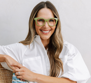 Green eyeglass frames on smiling woman in white shirt