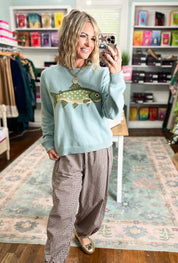 Sage sweater featuring a green fish graphic across the front