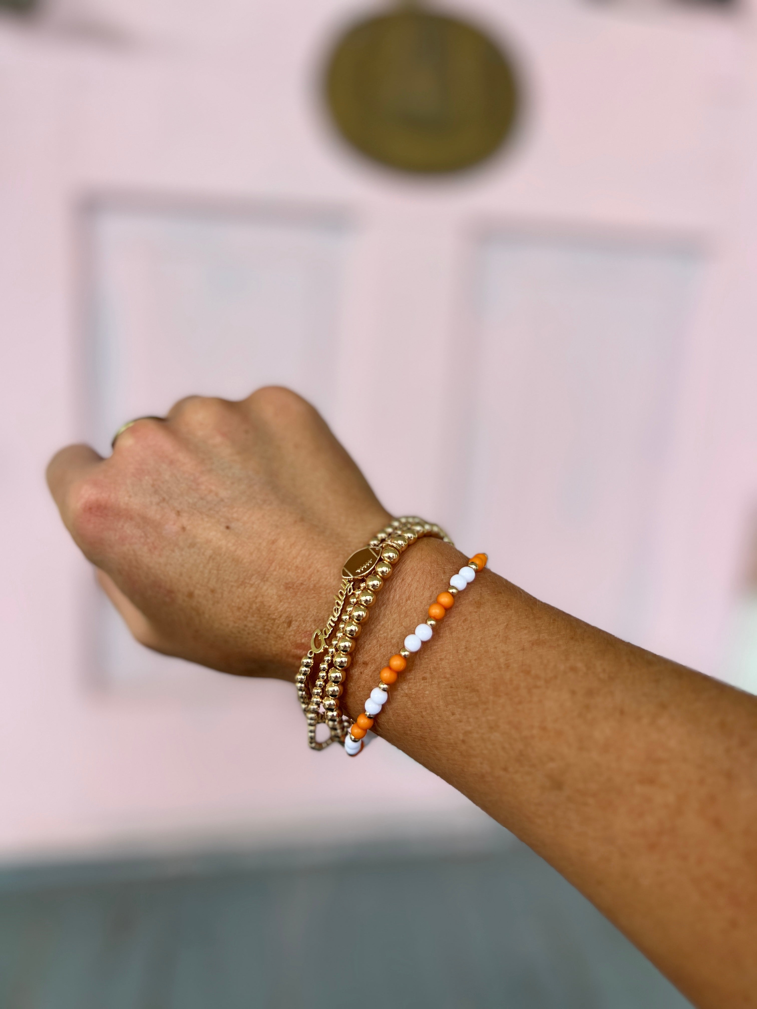 Gold chain bracelets with orange and white football charms