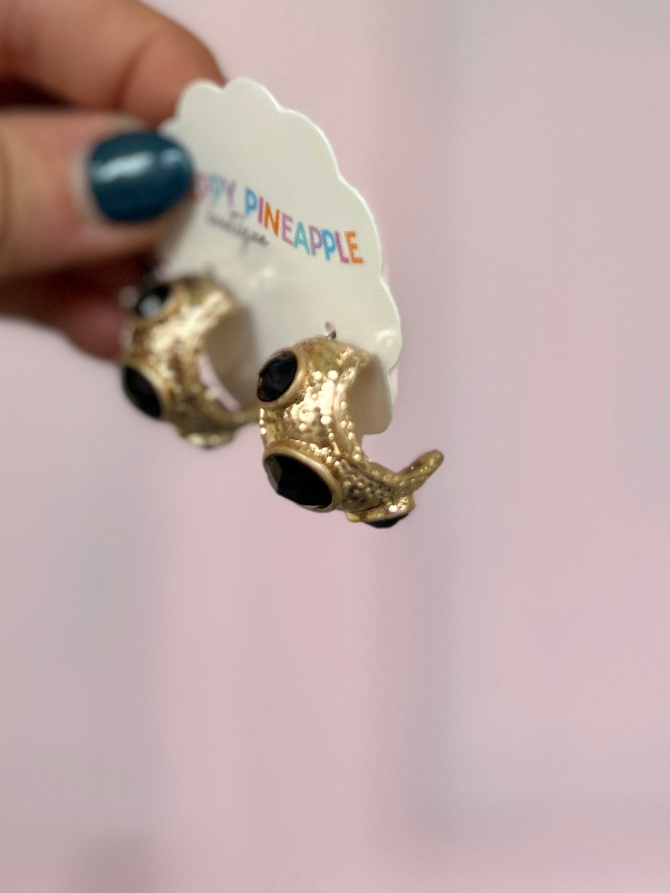 Gold-tone earring with black faceted stone and ornate sculpted bezel
