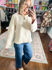 Ecru wide-sleeve sweater with crew neckline and ribbed cuffs, worn with blue jeans.