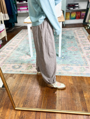 Brown gingham pants shown from the side, with a relaxed fit and full-length legs.