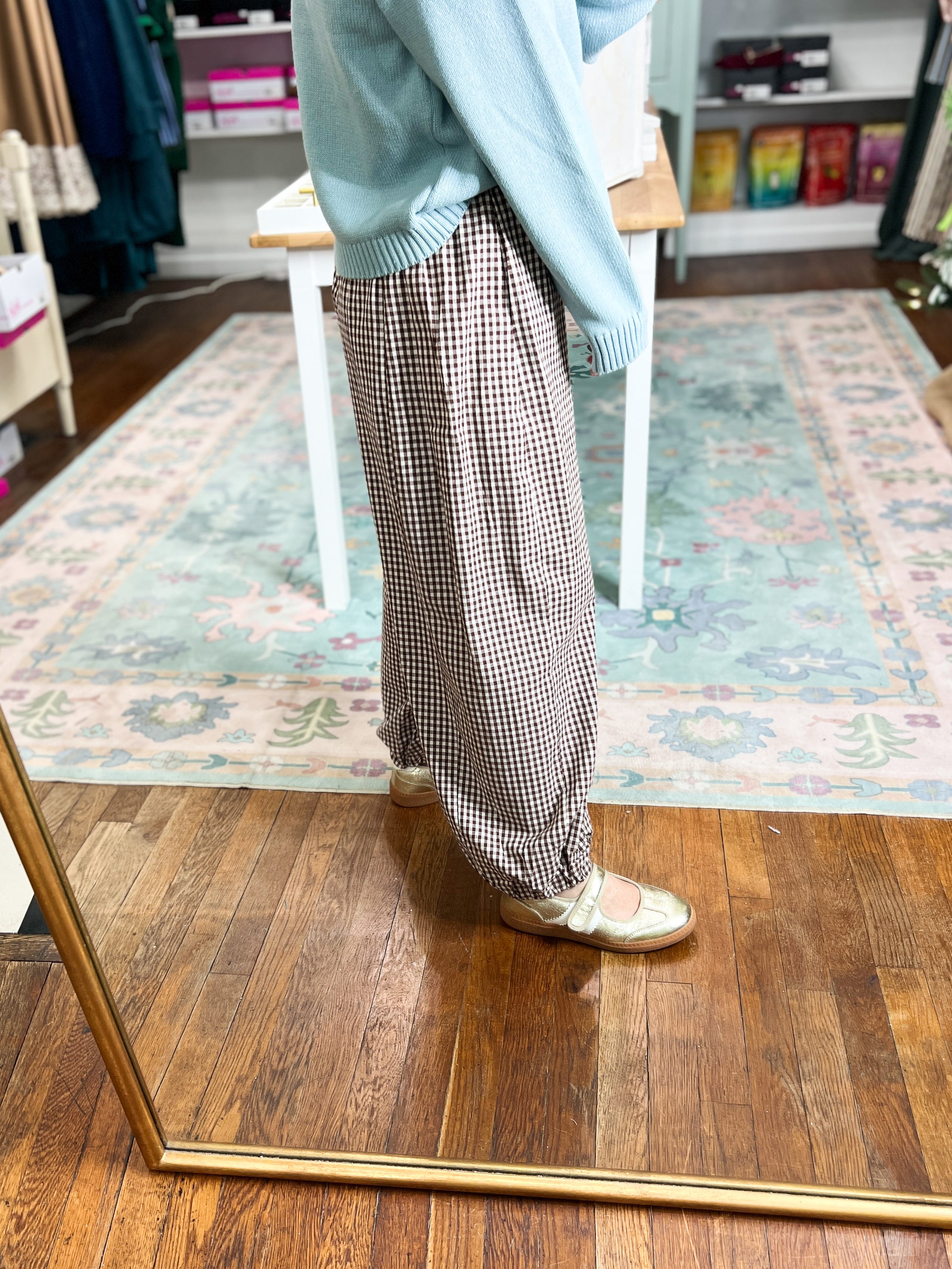 Brown gingham pants shown from the side, with a relaxed fit and full-length legs.