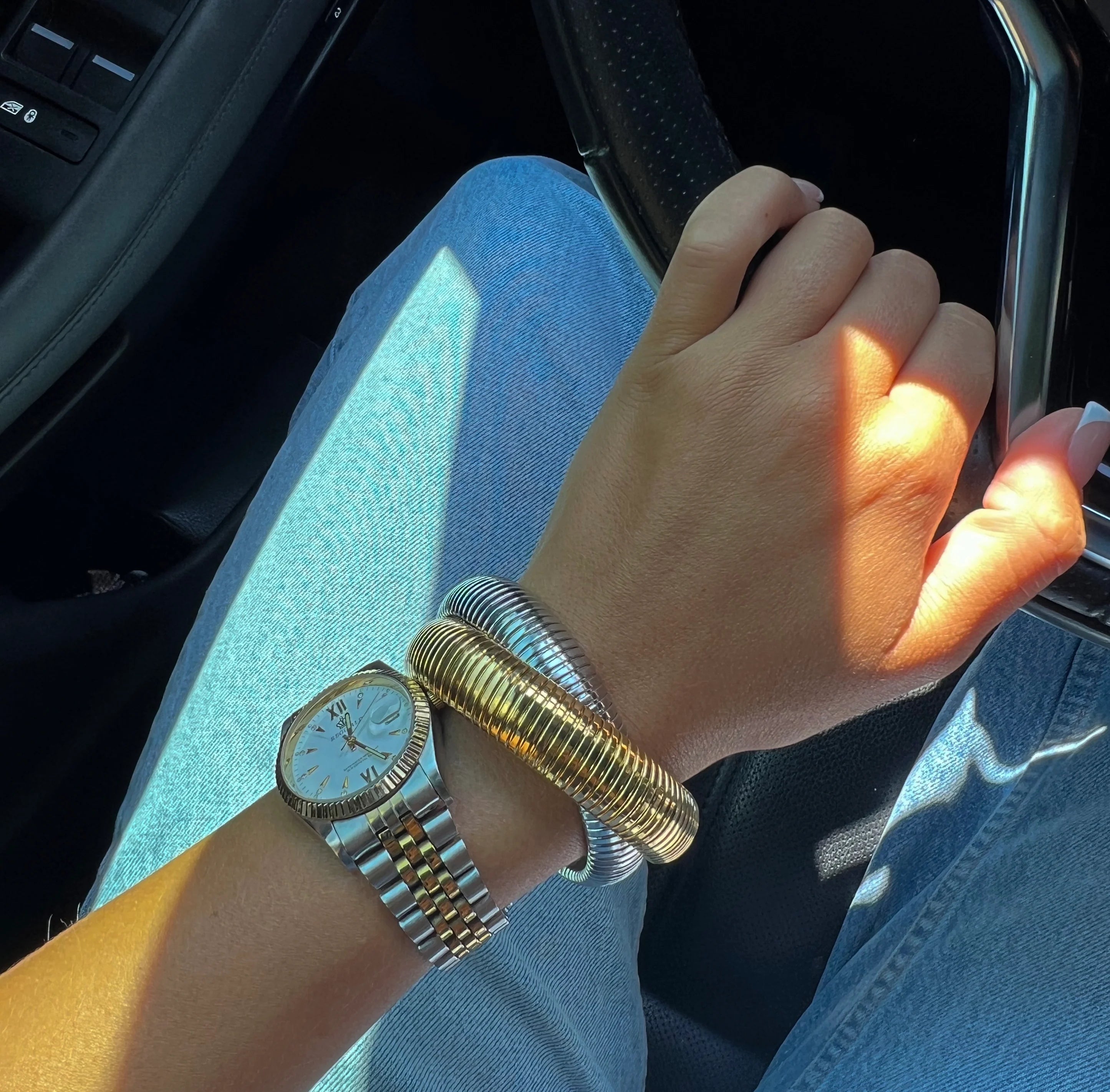 Gold spiral bangle bracelet with silver mesh band on wrist