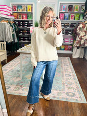 Ecru wide-sleeve knit sweater, long sleeves with ribbed trim, paired with blue jeans.