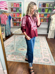 Burgundy embroidered blouse with long puff sleeves, white pattern yoke, and curved hem