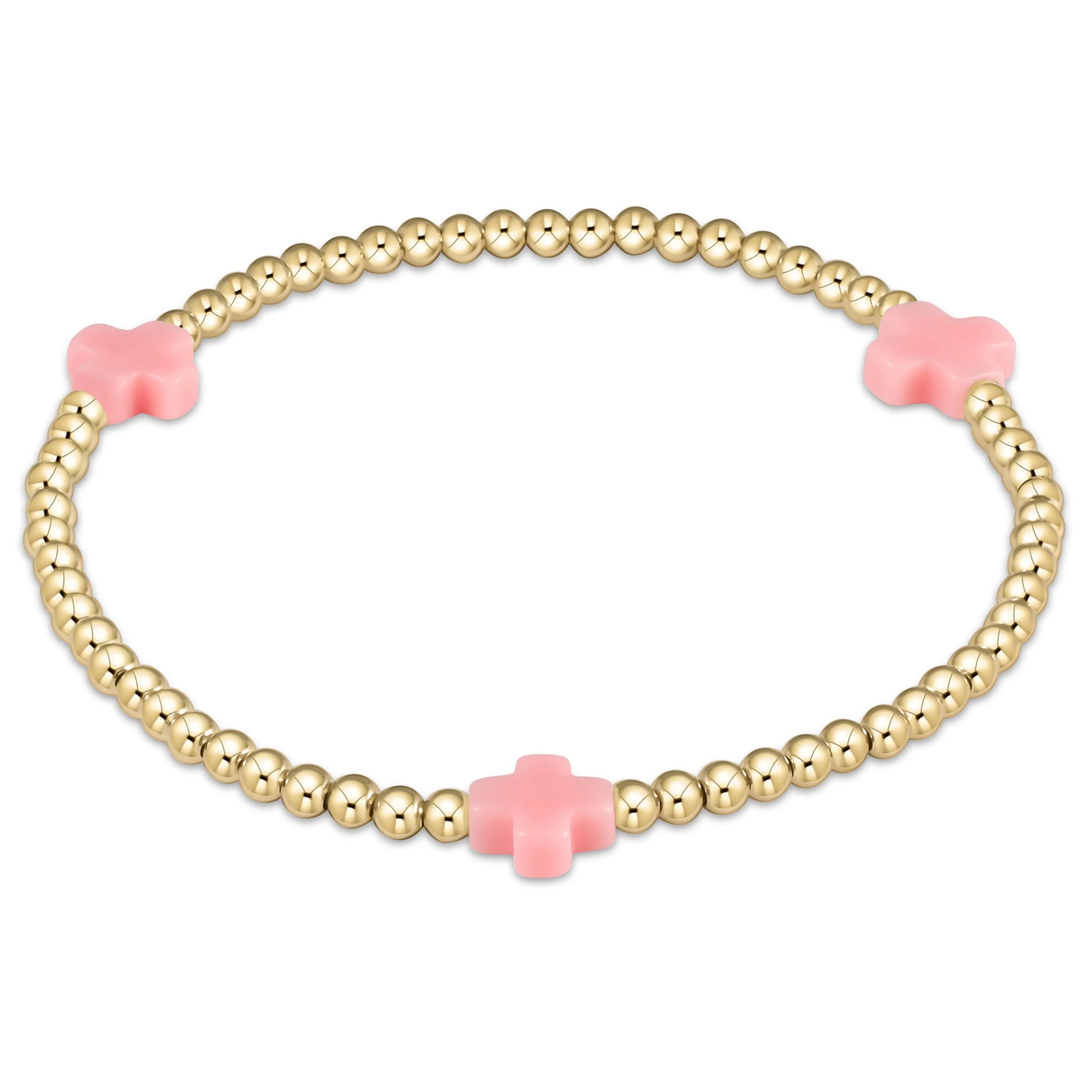 Gold bead bracelet with pink cross charm centerpiece