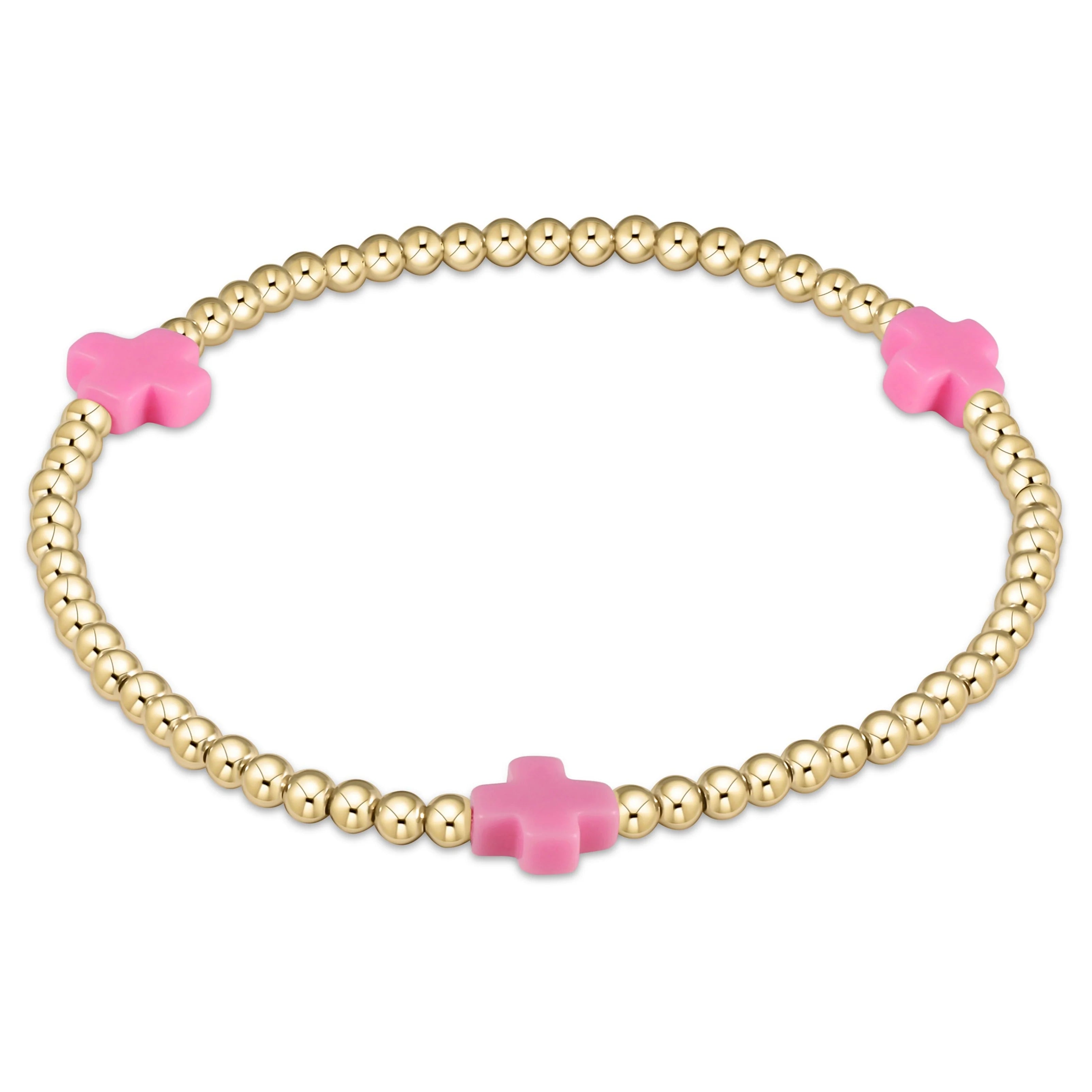 Gold beaded bracelet with bright pink cross charms