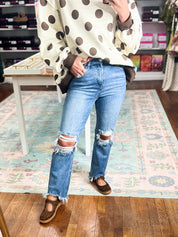 High-rise crop straight jeans in medium wash with ripped knees and frayed ankle hems