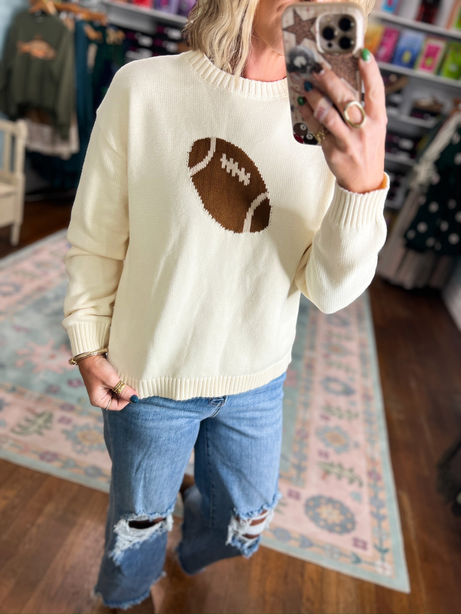Cream knit sweater with football applique at chest, ribbed cuffs and crew neck.