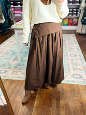 Brown midi skirt with gathered waist and tiered pleats, side view.