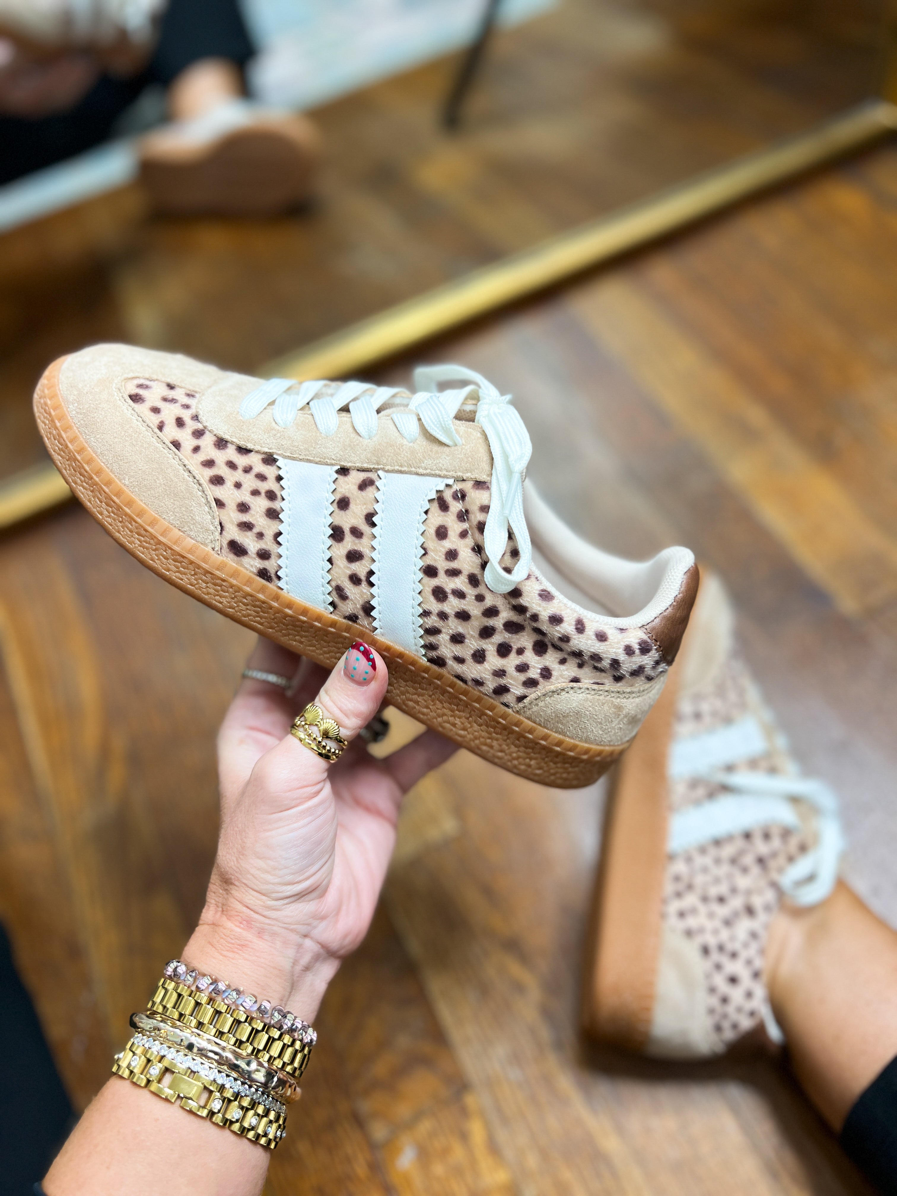 Side view of leopard-print mini sneakers with white laces and tan textured sole.