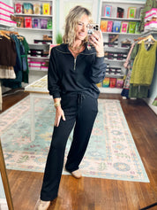 Black half-zip pullover with relaxed fit and raglan sleeves, zip at center front
