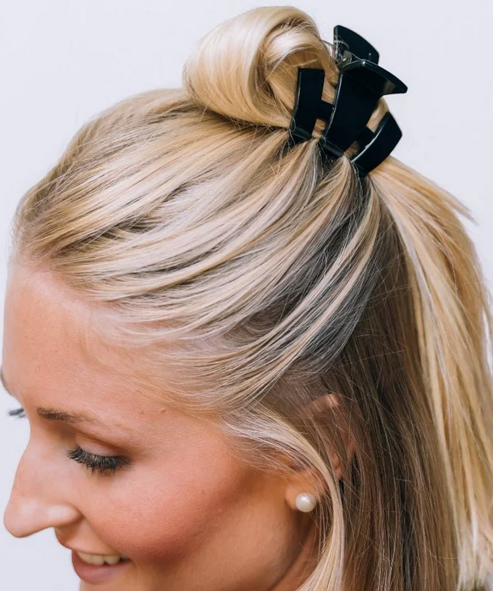 Black petite claw clip with three curved prongs, holding blonde hair back