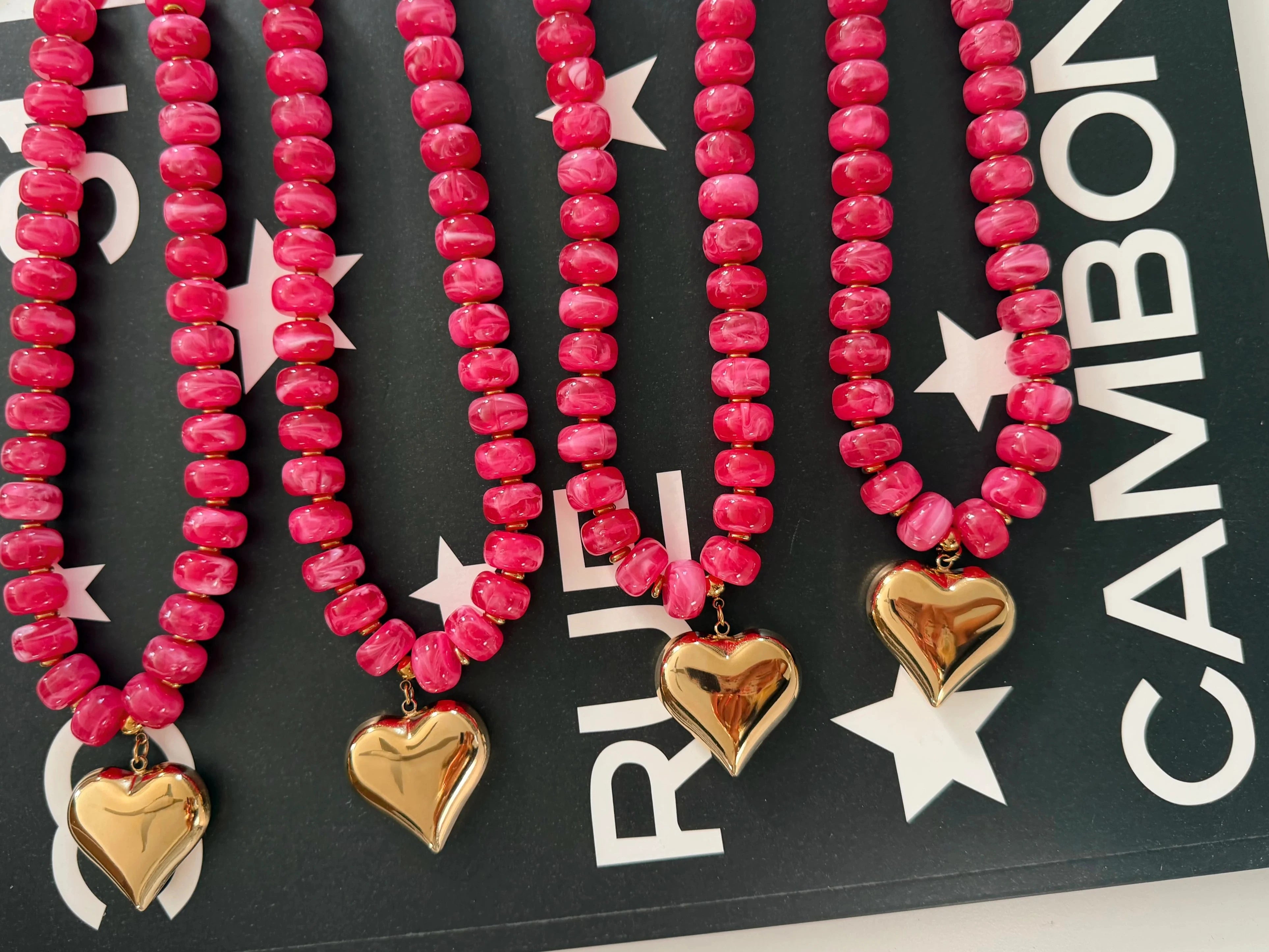 Pink beaded heart necklace with three gold-tone heart pendants