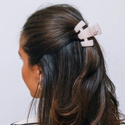 Petite almond beige claw clip securing dark hair at the side