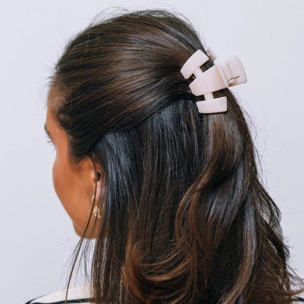 Petite almond beige claw clip securing dark hair at the side
