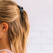 Jet black claw clip holding blonde hair in a side ponytail