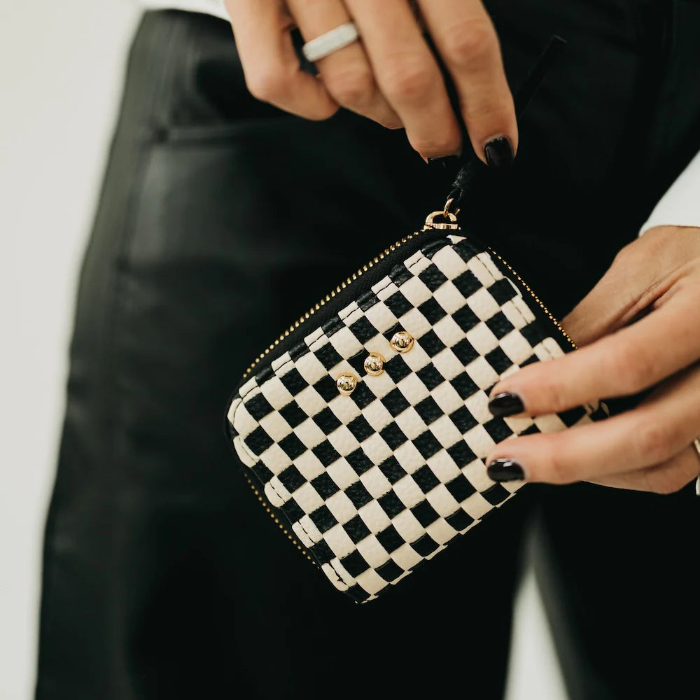 Black and white checkered pouch held by a person with a blurred background