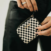 Black and white checkered pouch held by a person with a blurred background